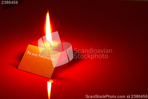 Image of Burning heart shaped candle and a Valentine's card