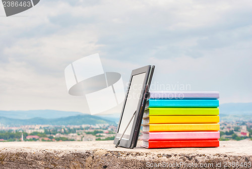 Image of Stack of colorful books with electronic book reader