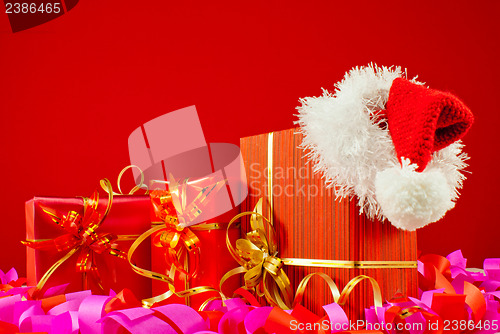 Image of Christmas presents with Santa's hat against red background