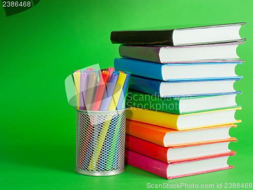 Image of Stack of colorful books and socket with felt pens