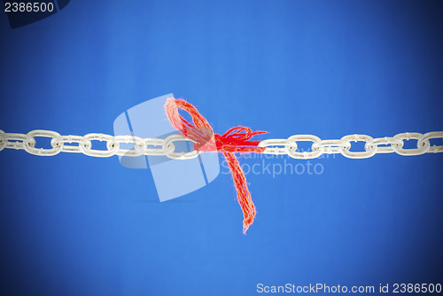 Image of Broken chain connected with red threads 