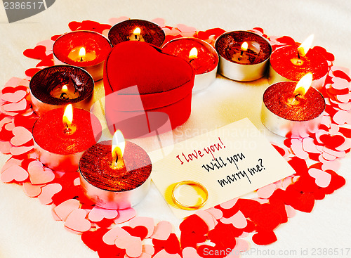 Image of Ring and a card with marriage proposal with candles