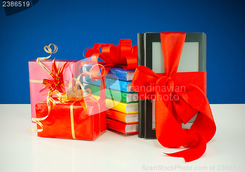 Image of Christmas presents with electronic book reader against blue background