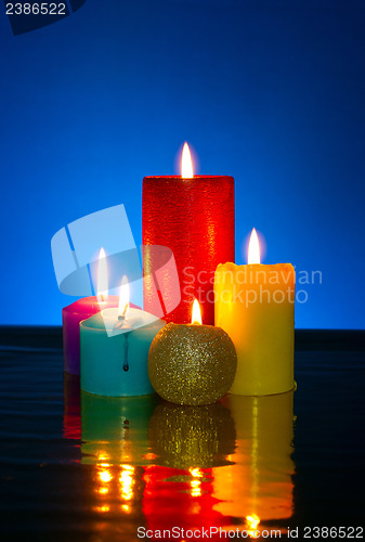 Image of Five burning colourful candles against blue background