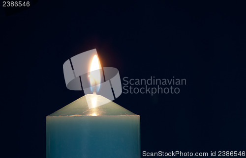 Image of Close up of burning candle against dark blue background