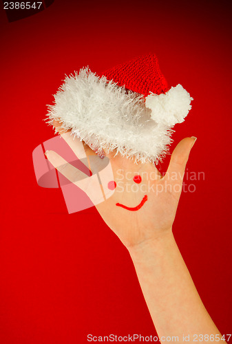 Image of Human's palm with smile on it wearing Santa's hat