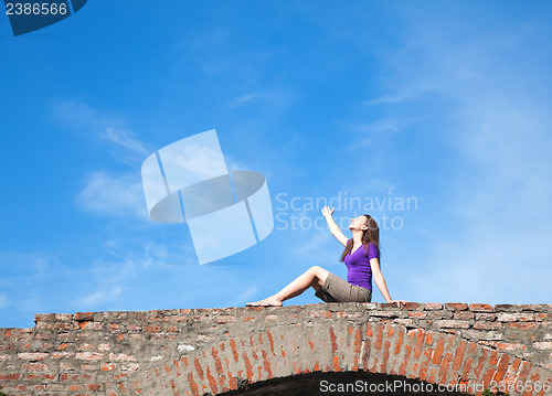 Image of Young woman sitting with raised hand