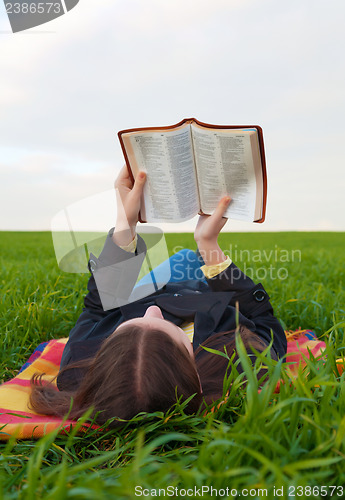 Image of Teen girl reading the Bible outdoors