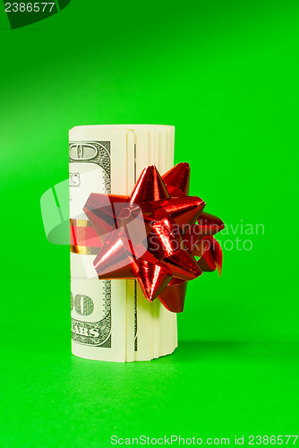 Image of A wad of US one hundred dollar bills tied up with red ribbon