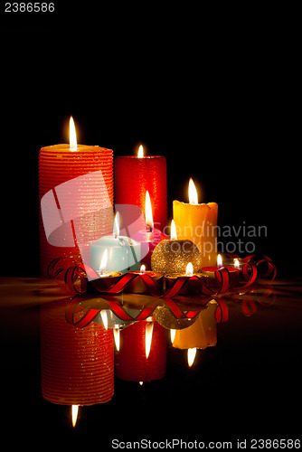 Image of A lot of burning colorful candles against black background