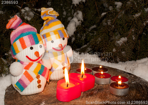 Image of Two snowmen with two burning heart shaped candles