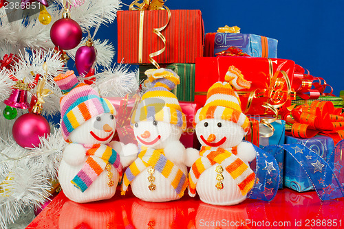 Image of Three snowmen in front of the Christmas presents over the blue b