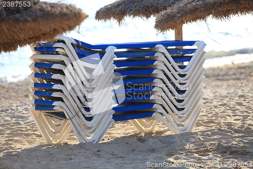 Image of Stack of recliner chairs on a beach