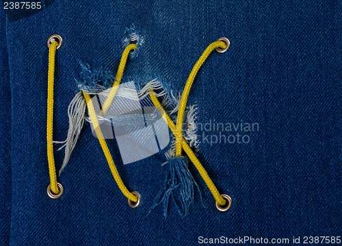 Image of Blue jean with hole and crisscross yellow lacing