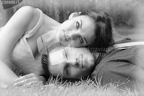 Image of Black and White version of a young couple laying on the grass wi