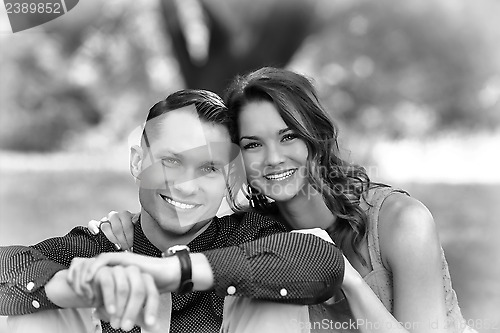 Image of Black and White version of a happy young couple posing seated on