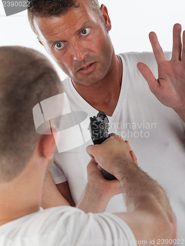 Image of Scared man being threatened by a man with a handgun