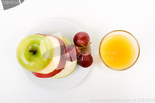 Image of Apple, grapes on a plate and a glass of orange juice