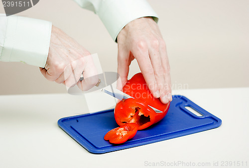 Image of man cuts the a red pepper. Hands close-up