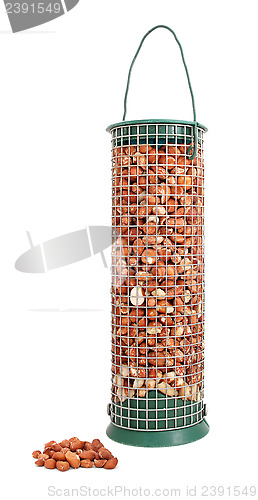 Image of Bird feeder filled with peanuts and some nuts lying loose