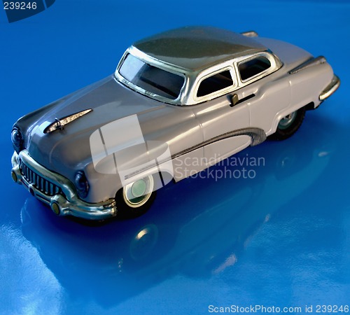 Image of old gray toy car against a blue reflective background