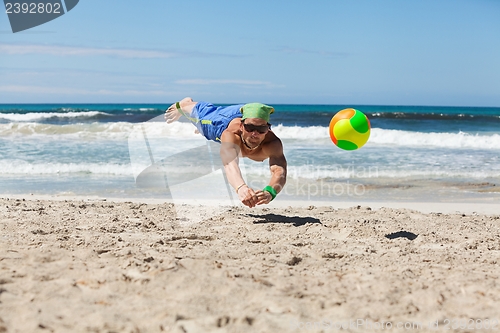 Image of attractive adult man playing beach volleyball in summer 