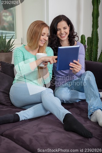 Image of two young attractive girl with tablett pc on couch