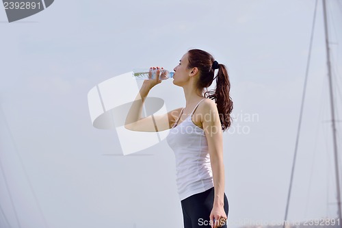 Image of Young beautiful woman drinking water after fitness exercise