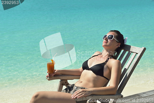 Image of Beautiful young woman with a drink by the sea