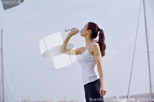 Image of Young beautiful woman drinking water after fitness exercise