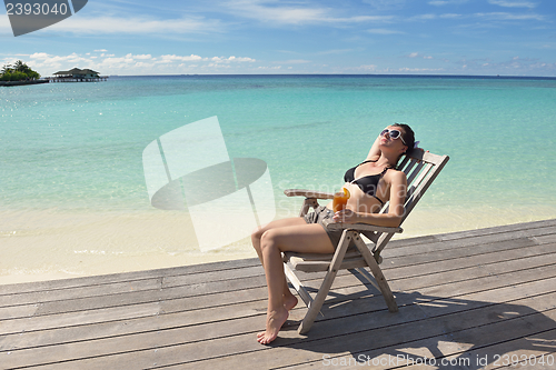 Image of Beautiful young woman with a drink by the sea