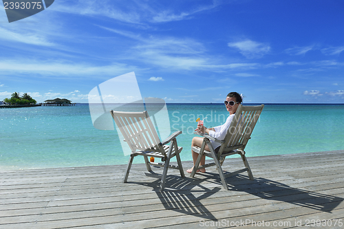 Image of Beautiful young woman with a drink by the sea