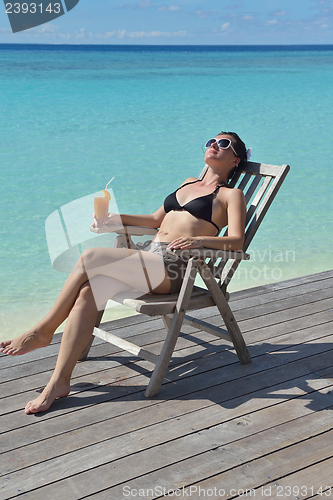 Image of Beautiful young woman with a drink by the sea