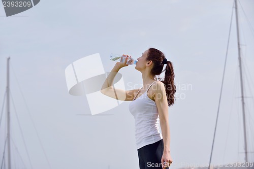 Image of Young beautiful woman drinking water after fitness exercise