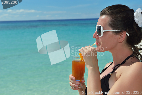 Image of Beautiful young woman with a drink by the sea