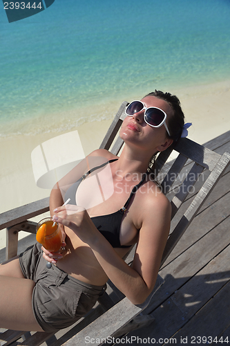 Image of Beautiful young woman with a drink by the sea