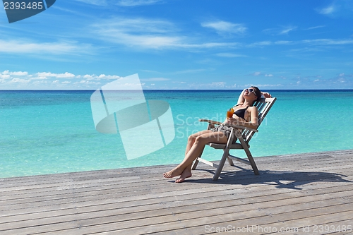 Image of Beautiful young woman with a drink by the sea