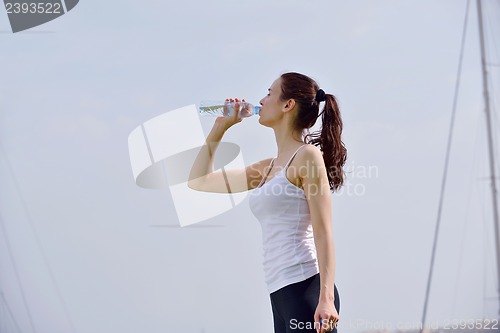 Image of Young beautiful woman drinking water after fitness exercise