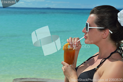 Image of Beautiful young woman with a drink by the sea