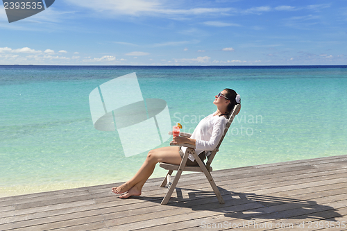 Image of Beautiful young woman with a drink by the sea