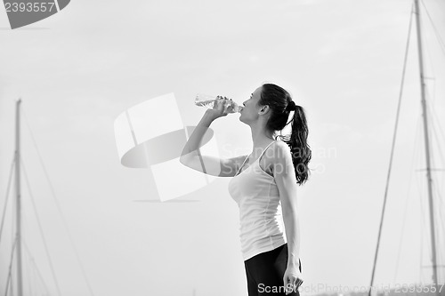 Image of Young beautiful woman drinking water after fitness exercise