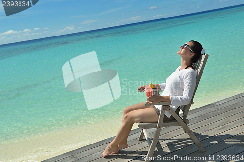 Image of Beautiful young woman with a drink by the sea