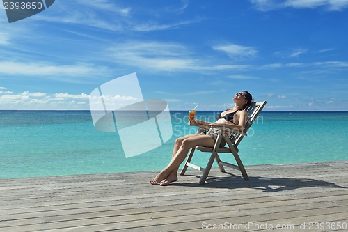 Image of Beautiful young woman with a drink by the sea