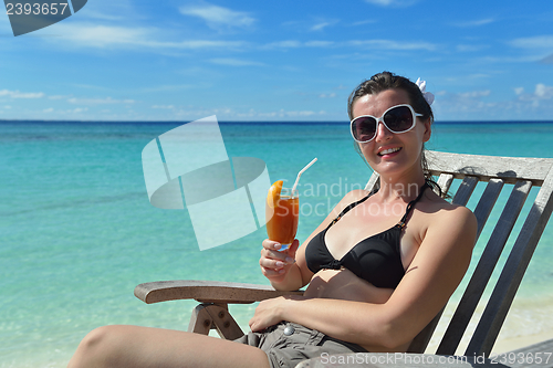 Image of Beautiful young woman with a drink by the sea