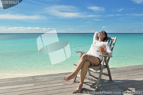 Image of Beautiful young woman with a drink by the sea