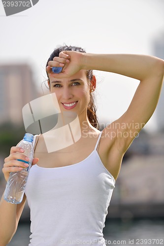 Image of Young beautiful woman drinking water after fitness exercise