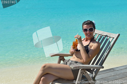 Image of Beautiful young woman with a drink by the sea