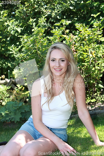 Image of Smiling beautiful woman in the shade of a tree