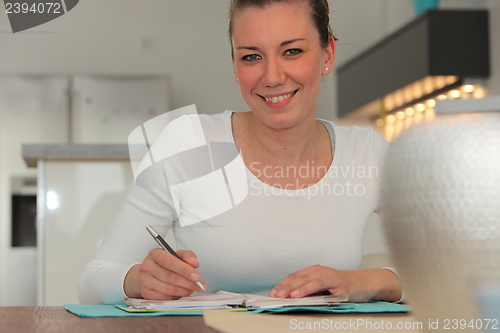 Image of Smiling woman writing notes in her dining room