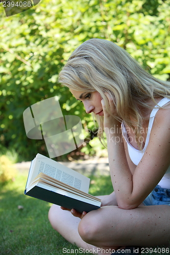 Image of Young woman reading a book in the garden